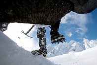 Mountaineer climbing snow covered mountain with crampons and ice axe