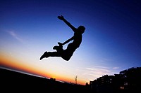 Parcours: A boy practicing jumps to the dusk in the beach