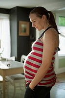 A pregnant woman in her kitchen in her 27th week of pregnancy.