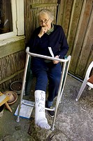 Old lady sitting in a chair outside and her leg is in a cast (plaster)