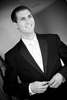 groom smiling, buttoning up suit