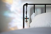 Jewelled cross hanging from metal bedhead