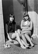 Sixties, black and white photo, people, two young girls, aged 16 to 18 years, woman friends, girlfriends, sitting in a porchway and enjoy the sun, bar...
