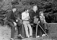Seventies, black and white photo, people, grandparents and two grandchildren take a walk, sitting on a wall and have a rest with a small picnic, grand...