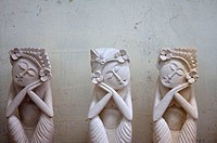 Three white stone figures of women that seem to be sleeping in sitting positions in Ubud, Bali.