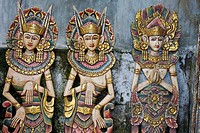 Three wooden figures of Balinese dancers in traditional dress in Ubud, Bali.