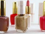 Make up grouping. Red, brown, fuschia, and gold nail polish in bottles. With lipstick tubes in the background. Horizontal, Silo. Isolated.