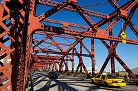 yellow cab and cars crossing a historic steel bridge over Willamette River, Portland, Oregon, USA