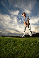 Wide angle image of a golfer lining up a shot with a dramatic sky in background.