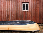 Detail of rowing boat beside traditional red timber boathouse in village of Mollosund on Bohuslan Coast of Sweden