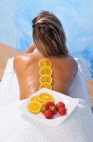 Dish with oranges and strawberries in the back of a young woman for a natural beauty treatment