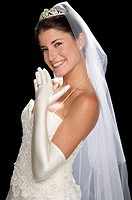 Bride in her 20s smiles at the camera in a studio setting