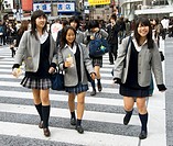 Three young Japanese schoolgirls crossing street at Shibuya in central Tokyo Japan