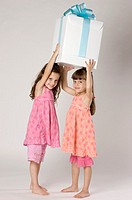 Four year old twins with a big present in a studio setting