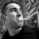Close-up of man in alley, smoking a cigarette