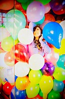 Young woman fantasizes in a shower filled with colorful balloons
