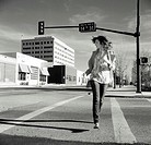 Young woman, running across empty downtown street