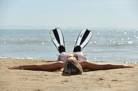 Girl with diving fins lying on the beach
