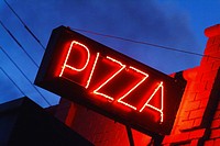 A neon pizza sign against a night sky