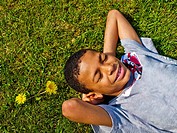 young boy lying on grass, below camera, african american, multiracial, vertical