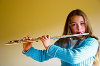 A young female music student playing the flute