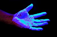 Hand covered in UV sensitive solution under Ultra Violet light source to detect germs and other undesirable materials to be washed off  before proceed...
