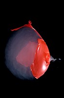 A smoke filled red balloon bursting when shot with an air rifle  Sound wave visible and pellet exiting