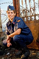 Military girl posing with a spike fence in background