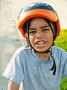 6 year old multiracial boy with bike helmet on  Making a funny face