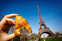 hand holding a croissant in Eiffel Tower, Paris