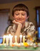 Boy, age 10, looks at his birthday cake during party.