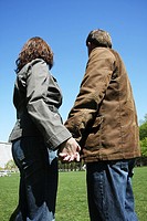 Couple holding hands and looking away on a sunny day in a park