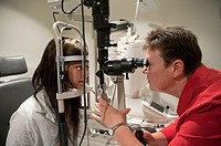 Teenage girl having her eyes checked for contact lens prescription by an optometrist