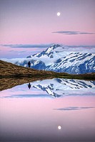 Mt Aspiring, tramper enjoys moonrise at dusk, Cascade Saddle tarn, Mount Aspiring National Park, Otago, New Zealand