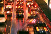 Blurred image of a traffic jam with cars seen from behind with their red lights and reflections on the wet street after a heavy rain at night, Central...