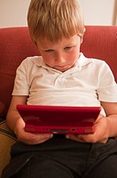 A  close up picture of a six year old boy playing on a nintendo DS handheld computer game console in the Uk