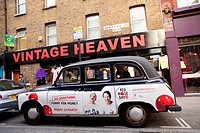 Taxi on Brick Lane with an advertising sign of a vintage shop