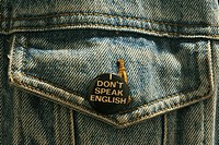 button saying ´I don´t speak English´ on pocket of blue jean jacket