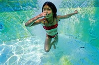 Young girl holding her breath underwater in a swimming pool, Provence, France.