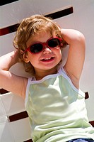 Child with sunglasses relaxing on deck