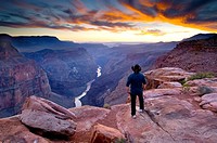 Person standing at the edge of steep rugged cliffs above the Colorado River at sunset, Toroweap, Grand Canyon National Park, Arizona