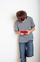 10 year old boy playing with a Nintendo DS handheld games console in the studio