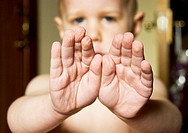 A child shows his hands after swimming - the skin of his fingers and palms is all wrinkled from being in the water for a while