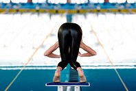 Young woman about to dive in swimming competition