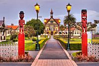 Rotorua Museum entrance pathway lined by lamps and Maori wooden carved figures, dusk, Government gardens, Rotorua.