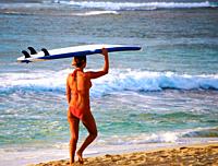 Girl carries surfboard on beach, Hawaii, USA