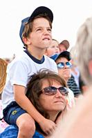 Young boy on mom´s shoulders watches the skys during air show at NAS Jacksonville, Florida