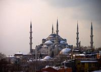 Shy sunrise in winter on the snowy Sultan Ahmed Mosque Turkish: Sultanahmet Camii also called blue mosque, Istanbul, Turkey, with the fogy Bosphorus i...