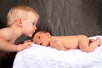 A two year old boy kisses his newborn baby brother
