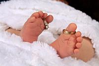 A newborn baby´s feet, with the parents´ wedding rings on his toes